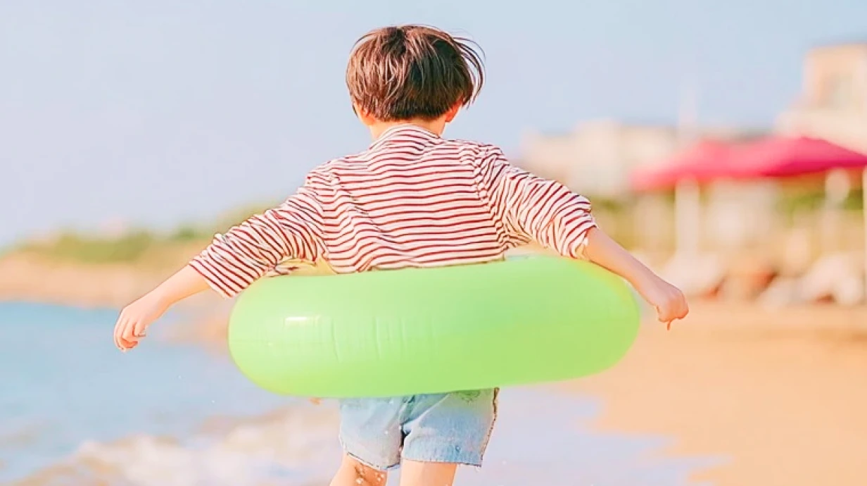 un enfant avec une bouée verte sur la plage