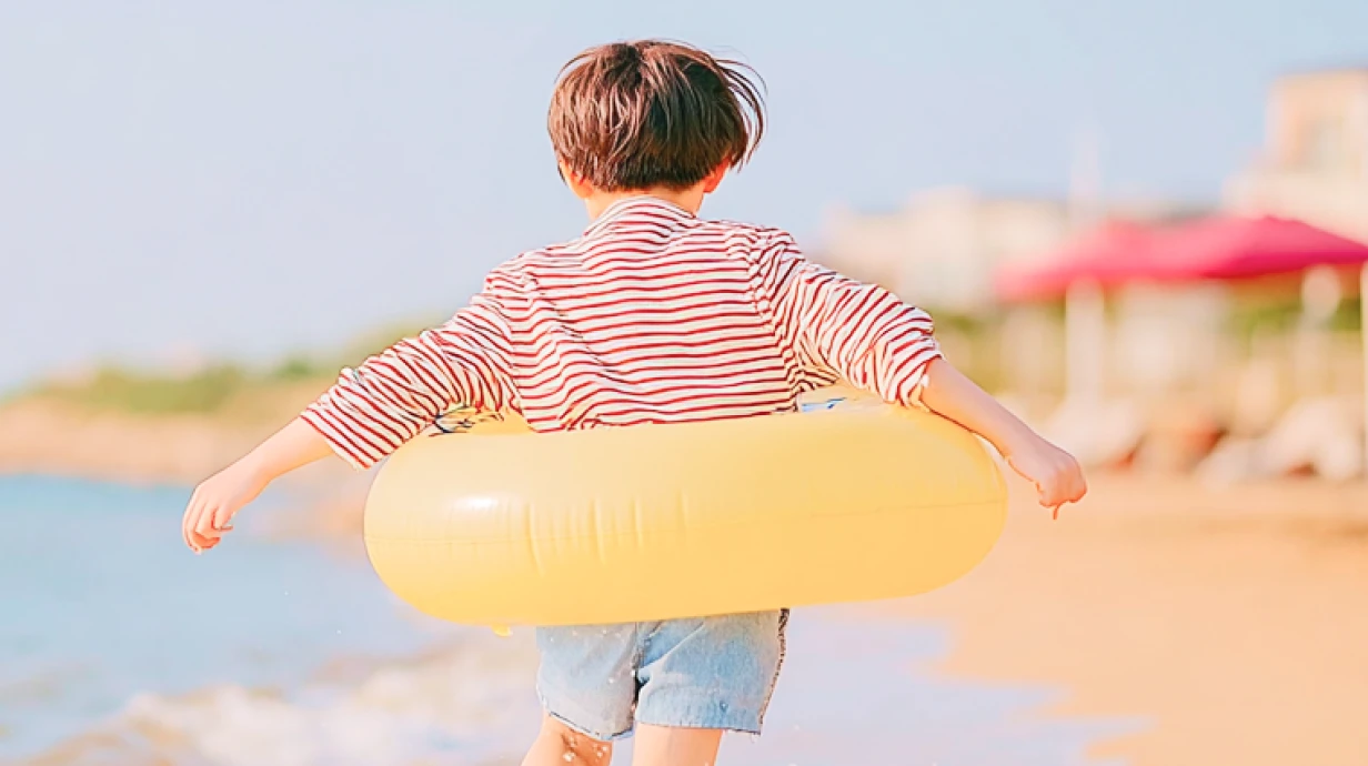 un enfant avec une bouée de natation jaune sur la plage