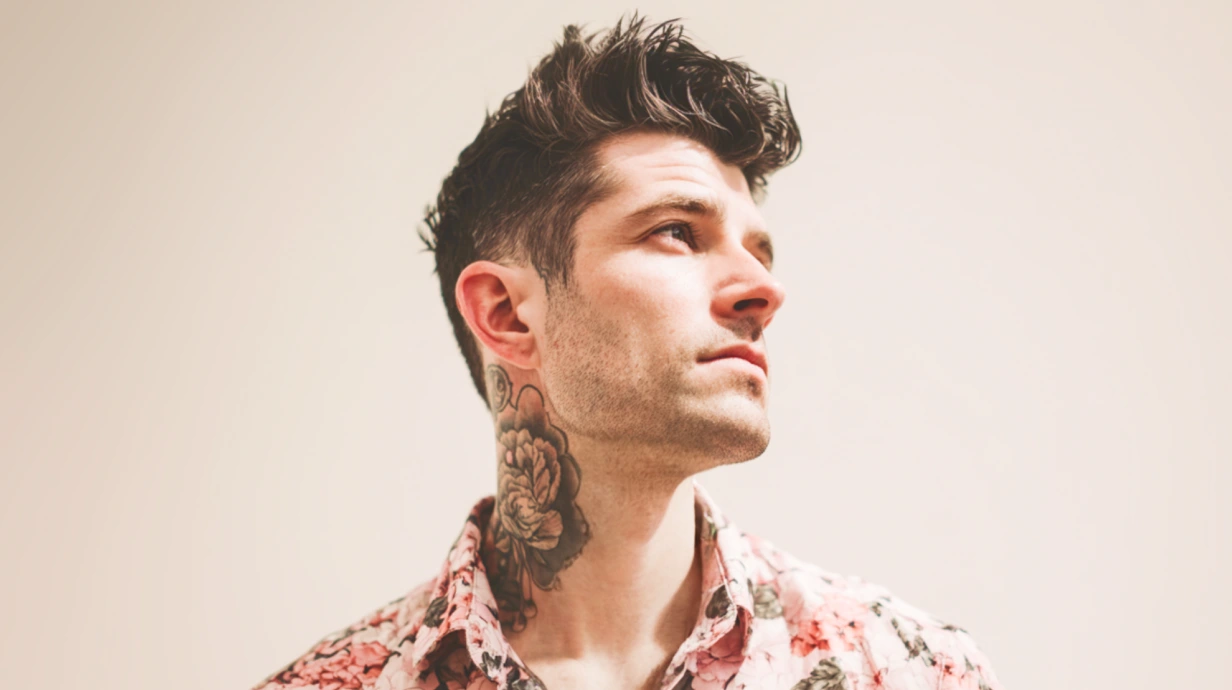 un homme en chemise colorée avec un tatouage sur le cou